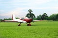 Ultralight aircraft on green grass near trees Royalty Free Stock Photo