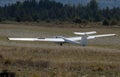 Ultralight glider plane flying near mountains, landing on earth aerodrome