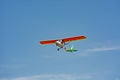 Ultralight plane flies of blue sky and clouds