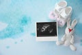 Ultrasound photo, baby shoes and toy on color background, top view