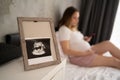 ultrasound photo of fetus in frame, pregnant woman on bed on background, pregnancy and ultrasound control Royalty Free Stock Photo
