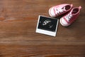 Ultrasound picture and baby shoes on wooden background, top view Royalty Free Stock Photo