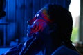 Ultraviolet black light glowing bodyart processing on young woman`s face. Pink and purple dyes in cold blue light Royalty Free Stock Photo