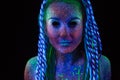 Ultraviolet make-up on the face of a young woman in blue colors, portrait of an alien on a black background. Royalty Free Stock Photo