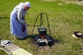 Ulyanovsk, Russia - July 16, 2022: Woman cooking food on fire in a pot. Historical reconstruction. Middle Ages