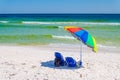 Umbrella and chairs set up at beach shoreline.