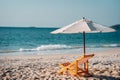 Umbrella and deck chair on the shore of a tropical island against the backdrop of the azure sea and blue sky. Vacation Royalty Free Stock Photo