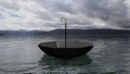 Umbrella floating on water, with distant mountains and cloudy sky