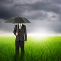 Umbrella man standing to raincloud in grassland with umbrella