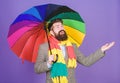 An umbrella is needed on a rainy day. Autistic or rain man holding colorful umbrella. Autism. Bearded man checking if it