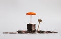 An umbrella on a pile of coins with small sign.