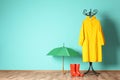 Umbrella, rain coat and boots near color wall Royalty Free Stock Photo