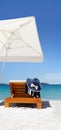 Umbrella and sunbed on the beach with hat, and towel Royalty Free Stock Photo