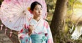 Umbrella, traditional and Japanese woman in park for wellness, fresh air and thinking outdoors. Travel, culture and