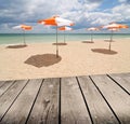 Umbrellas on the beach and empty wooden deck table. Royalty Free Stock Photo