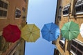 Umbrellas of different colors over the street with blue sky as background Royalty Free Stock Photo