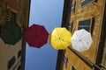 Umbrellas of different colors over the street with blue sky as background Royalty Free Stock Photo