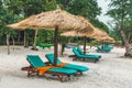 Umbrellas made of straw and chaise longue made of wood on a wonderful tropical beach, Beautiful beach, azure sea and white sand, Royalty Free Stock Photo