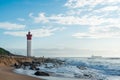 Umhlanga Rocks Lighthouse with fishermen and people walking on the promenade. Ship on the Indian Ocean in the background