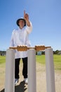 Umpire signalling six while standing behind stumps