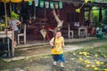 Unacquainted Local Fat boy Running in the rain while hold the toy Gun in his hand near the Local Shop in the rural of Thongphaphum