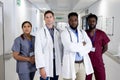 Unaltered portrait of diverse group of serious doctors standing in hospital corridor