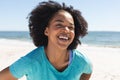 Unaltered portrait of happy african american woman looking at camera and smiling on beach