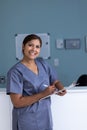 Unaltered portrait of happy asian female doctor writing on clipboard smiling in hospital corridor Royalty Free Stock Photo