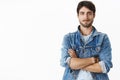 Unaltered shot of charismatic handsome hot adult man with beard and blue eyes in stylish denim jacket over striped t