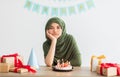 Unappy Indian teen girl in hijab having dull birthday party, celebrating holiday alone during covid lockdown, indoors Royalty Free Stock Photo