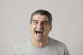 Unattractive 40s or 50s white funny man in sick and mad happy face expression screaming and shouting crazy isolated on grey Royalty Free Stock Photo