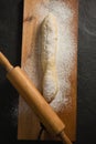 Unbaked loaf of bread with flour and rolling pin on cutting board