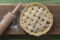 Unbaked pie with rolling pin on wooden surface