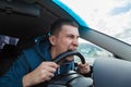 An unbalanced, goosey man bites a car steering wheel from anger while driving in a traffic jam or after an accident. A nervous and Royalty Free Stock Photo