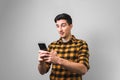 Unbelievable happy news. surprised man in yellow shirt holding a phone on grey background