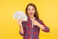 Unbelievable profit! Portrait of surprised excited girl in shirt pointing at dollars and expressing amazement shock, boasting of Royalty Free Stock Photo