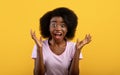 Unbelievable. Shocked african american woman screaming with open mouth, looking at camera over yellow background