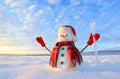 Unbelievable sunrise. Happy snowman in hat, scarf, red gloves with ice pikestaff is standing on the snow lawn. Mountains landscape