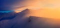 Fantastic scenery with a free rider and mountaineer, high mountains in snow and the fog with interesting colour from the sun. Royalty Free Stock Photo