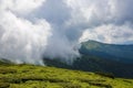 Unbelievable view from the green lawn to the mysterious fog, mountain with the old building and interesting sky with clouds