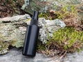 Unbranded black plastic spray and green forest moss. Front view, mockup. Cosmetic bottle container for branding of medicine or