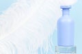 Unbranded blue shampoo, conditioner or shower gel bottle for branding and label on glass podium and large white ostrich feather on