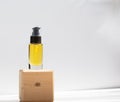 Unbranded bottle with body oil on wooden stand. Transparent glass container with dispenser. Repair, moisturizing for