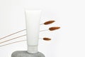 Unbranded flacon for cream, concealer, toiletry. Plastic cosmetic tube on stone and brown herbs Lagurus. Container for cosmetics