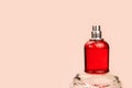 Unbranded perfume spray red bottle on crystal podium on pink background. Mockup with copy space. Bottle for branding and label,