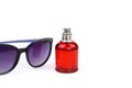 Unbranded perfume spray red bottle and purple sunglasses isolated on white background with copy space. Eau de toilette, front view