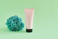 Unbranded pink squeeze bottle cosmetic tube with black screw cap and shower green sponge on green background. Cosmetic bottle Royalty Free Stock Photo