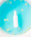 Unbranded skincare products white plastic bottle with dispenser and flacons. Tube for cream shampoo. Blue ocean water background, Royalty Free Stock Photo