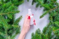 Unbranded white plastic spray bottle, female hand with red nails and fir tree on gray table. Natural organic spa cosmetics concept Royalty Free Stock Photo