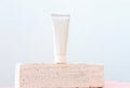 Unbranded white tube of cosmetic product on a pedestal or podium